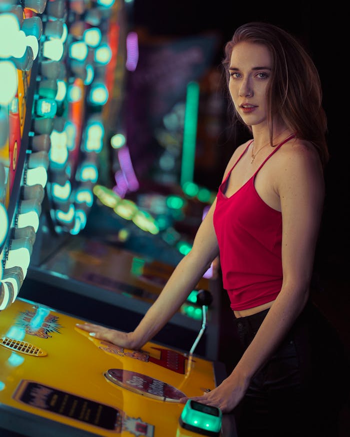 Stylish woman in red top at an illuminated arcade, enjoying a fun night out.